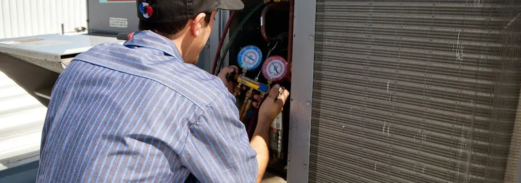 HVAC technician servicing a condenser unit in Duluth